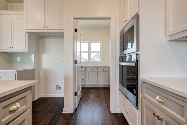 kitchen with dark wood-type flooring, white cabinets, appliances with stainless steel finishes, light countertops, and backsplash
