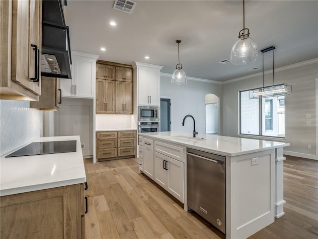kitchen with visible vents, a sink, ornamental molding, stainless steel appliances, and decorative backsplash