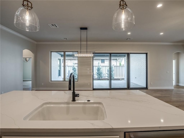 kitchen featuring arched walkways, visible vents, a sink, and a healthy amount of sunlight