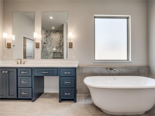 full bath featuring a freestanding bath, vanity, tile patterned flooring, and a marble finish shower