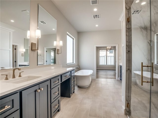 bathroom with visible vents, a freestanding bath, and vanity