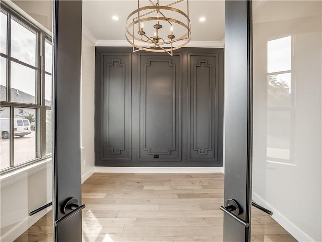 unfurnished dining area with light wood-type flooring, ornamental molding, recessed lighting, a chandelier, and baseboards