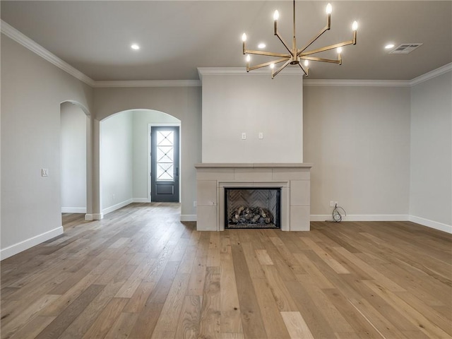 unfurnished living room featuring visible vents, baseboards, arched walkways, crown molding, and wood finished floors