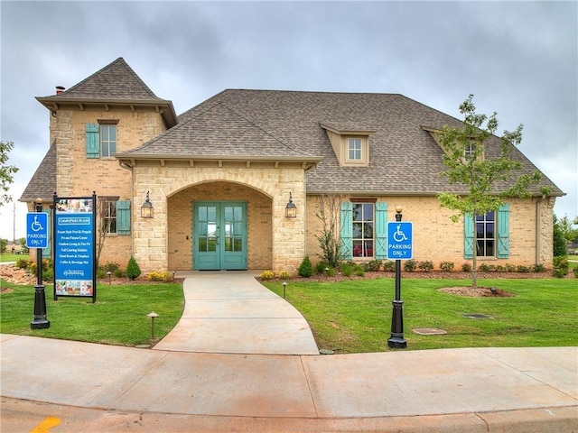 french provincial home featuring a front yard, brick siding, french doors, and a shingled roof