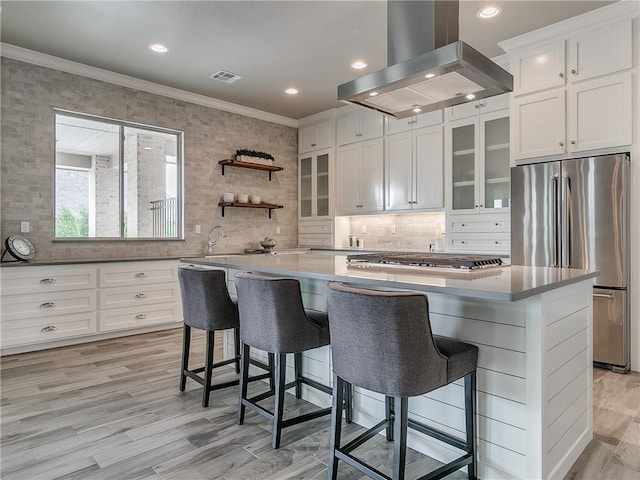kitchen featuring crown molding, white cabinetry, a center island, island exhaust hood, and stainless steel appliances