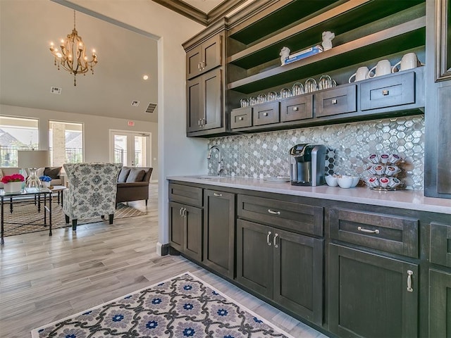 bar featuring tasteful backsplash, a chandelier, light wood-style flooring, visible vents, and a sink