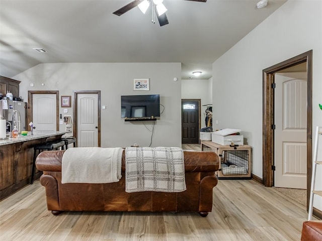 living room featuring light wood-style flooring, visible vents, ceiling fan, and lofted ceiling
