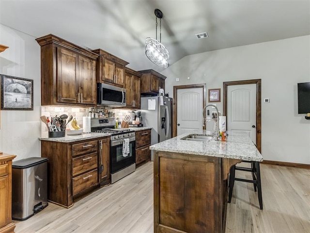 kitchen featuring tasteful backsplash, visible vents, a sink, a breakfast bar, and stainless steel appliances