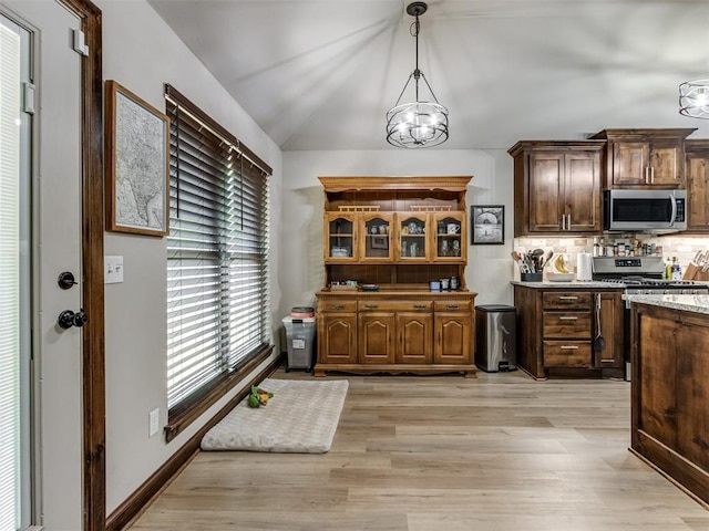 kitchen with tasteful backsplash, a notable chandelier, light wood-type flooring, stainless steel appliances, and hanging light fixtures