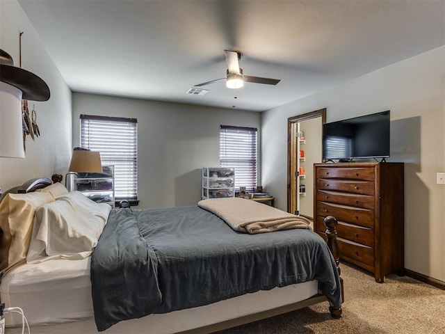 bedroom with multiple windows, light colored carpet, visible vents, and ceiling fan