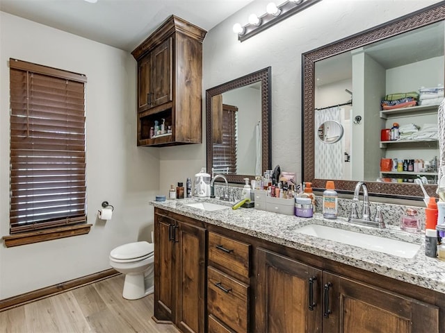 bathroom featuring double vanity, a sink, toilet, and wood finished floors