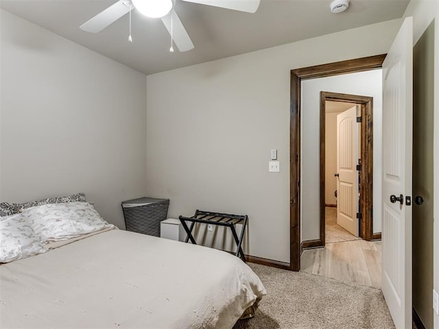 bedroom with light carpet, baseboards, and a ceiling fan