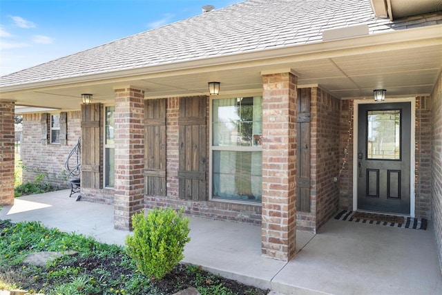 entrance to property featuring covered porch and brick siding
