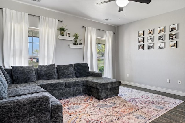 living room featuring dark wood-type flooring, visible vents, ceiling fan, and baseboards
