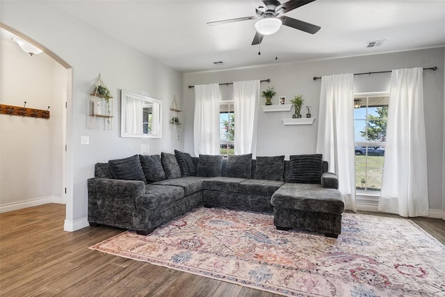 living room with visible vents, baseboards, arched walkways, a ceiling fan, and wood finished floors