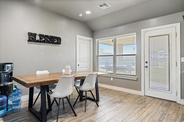 dining room with visible vents, baseboards, light wood-type flooring, and vaulted ceiling
