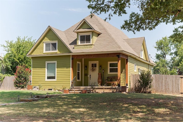 view of front facade with fence, a porch, and a front lawn