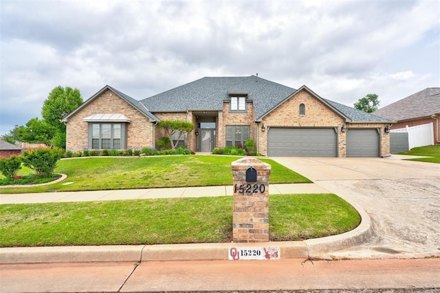 traditional-style home featuring roof with shingles, brick siding, a garage, a front yard, and concrete driveway