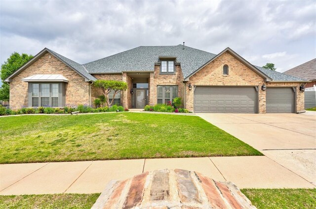view of front facade featuring roof with shingles, an attached garage, concrete driveway, and a front lawn