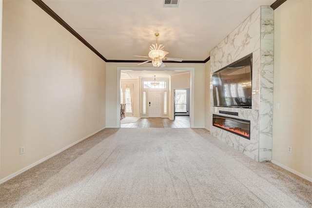 unfurnished living room featuring an inviting chandelier, ornamental molding, carpet, and a premium fireplace