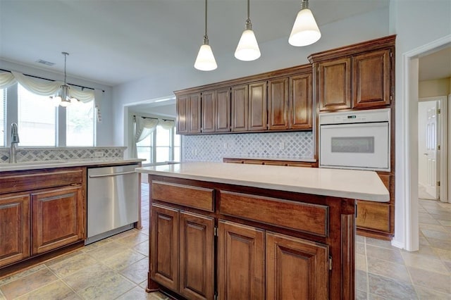 kitchen featuring dishwasher, white oven, light countertops, a sink, and backsplash
