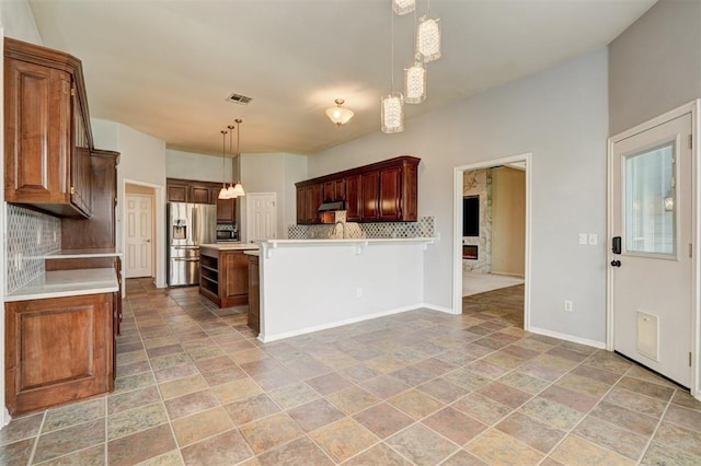 kitchen with baseboards, stainless steel refrigerator with ice dispenser, light countertops, tasteful backsplash, and stone finish flooring