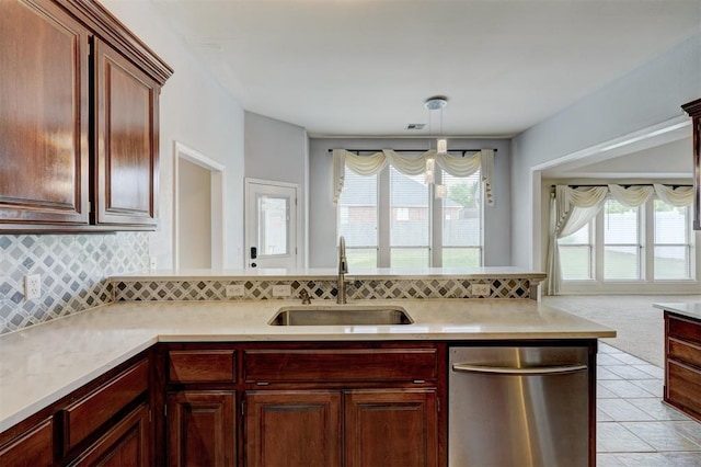 kitchen with stainless steel dishwasher, a sink, decorative backsplash, and light countertops