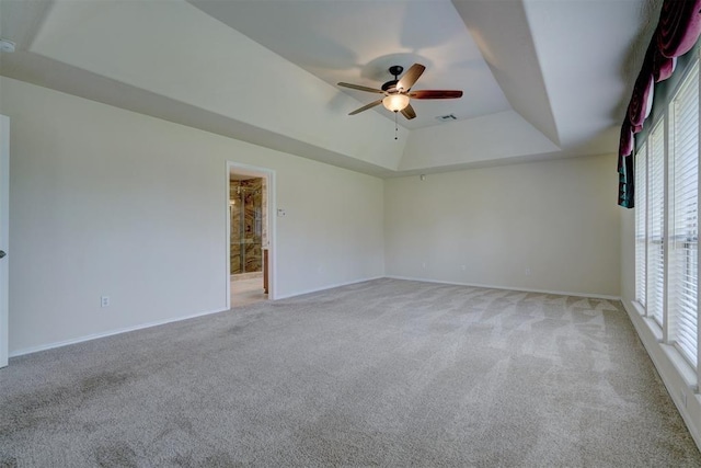 empty room with ceiling fan, light carpet, a raised ceiling, baseboards, and visible vents