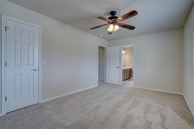 unfurnished bedroom featuring baseboards, ensuite bathroom, a ceiling fan, and light colored carpet