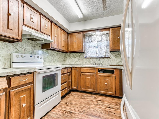 901 Richmond St, Yukon, OK 73099 - kitchen with brown cabinets, light wood finished floors, under cabinet range hood, a sink, and white appliances