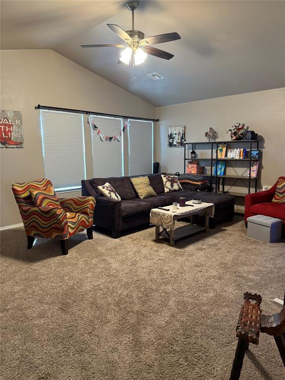 living area with visible vents, ceiling fan, carpet flooring, and lofted ceiling