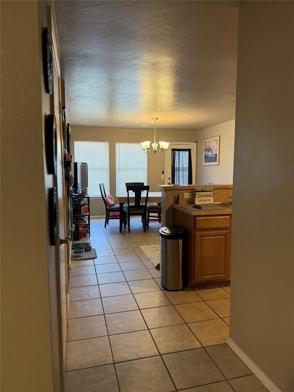 interior space with light tile patterned flooring, a notable chandelier, and baseboards