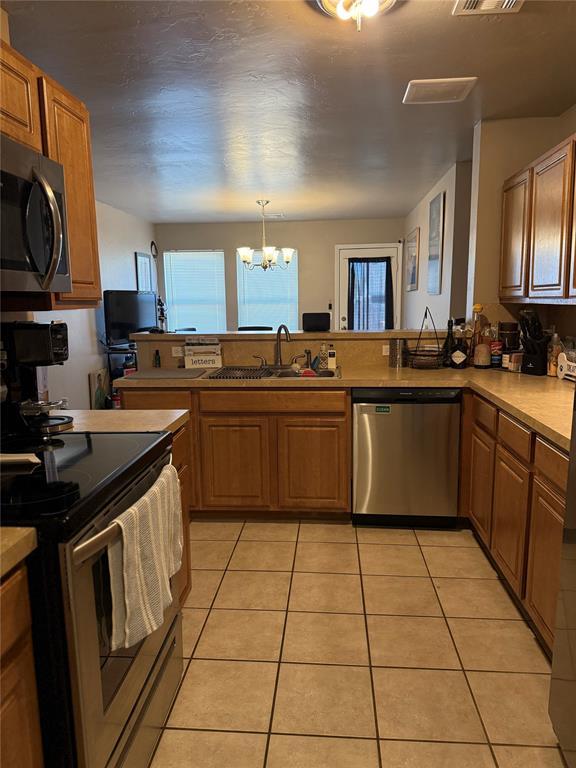 kitchen featuring stainless steel appliances, plenty of natural light, a sink, and a chandelier