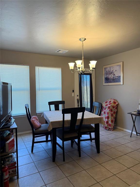dining area featuring light tile patterned floors, a wealth of natural light, a notable chandelier, and visible vents