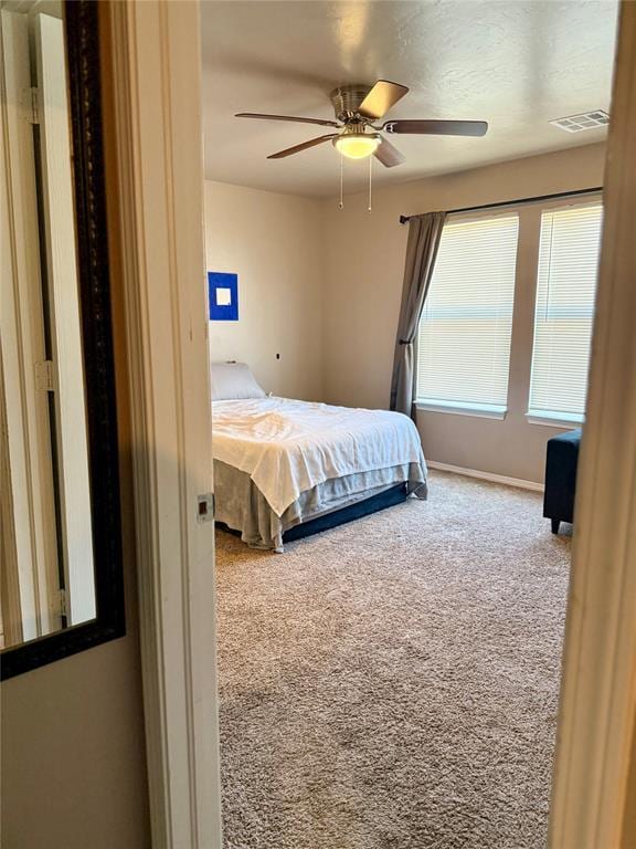 carpeted bedroom with ceiling fan, baseboards, and visible vents