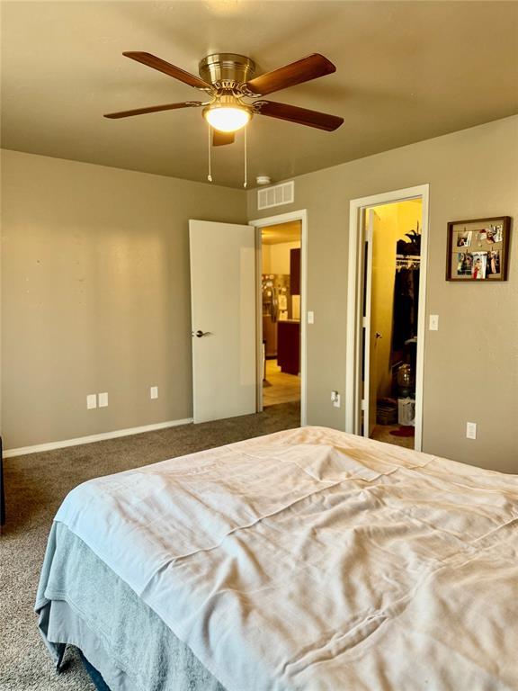 carpeted bedroom with a spacious closet, visible vents, ceiling fan, and a closet