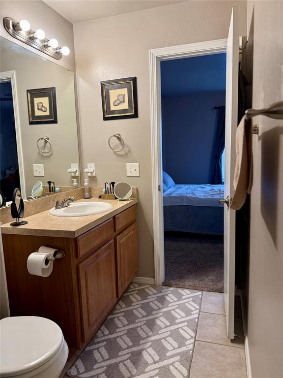 ensuite bathroom featuring ensuite bath, tile patterned flooring, toilet, and vanity