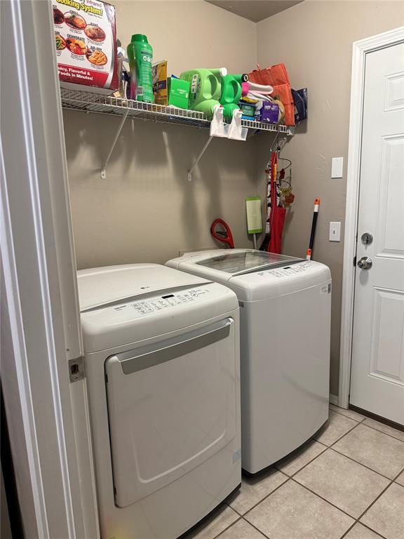 laundry room featuring laundry area, washing machine and clothes dryer, and light tile patterned floors