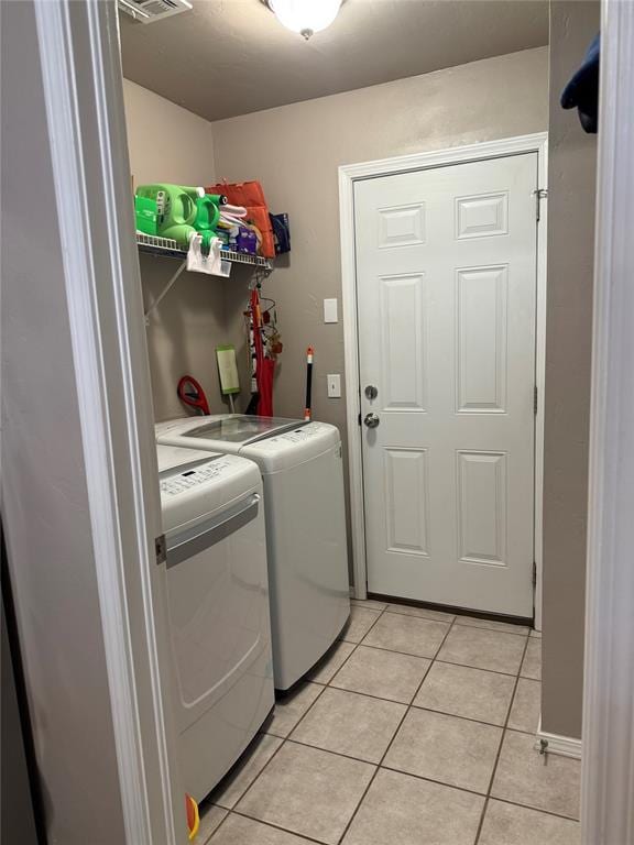 laundry room with washer and clothes dryer, light tile patterned floors, visible vents, and laundry area