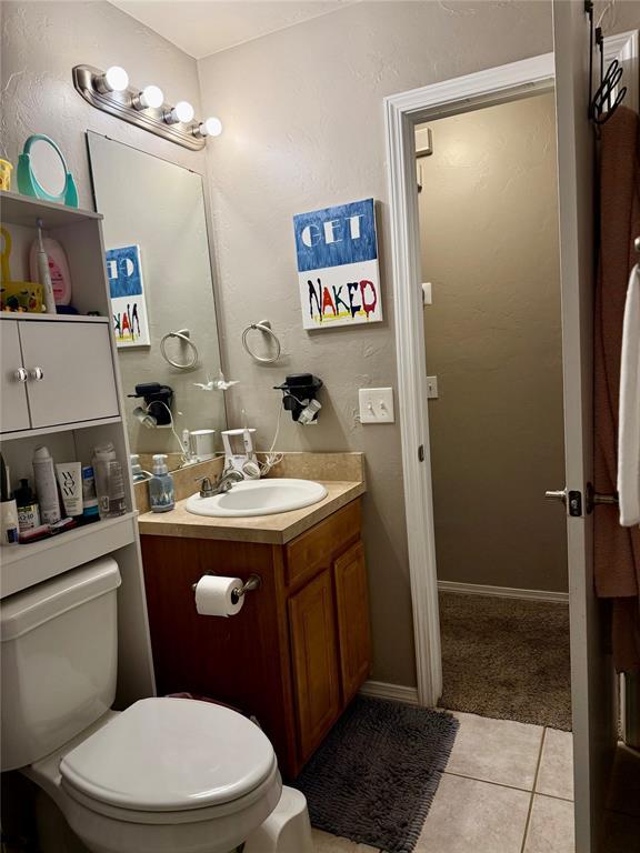 bathroom featuring toilet, vanity, and tile patterned flooring