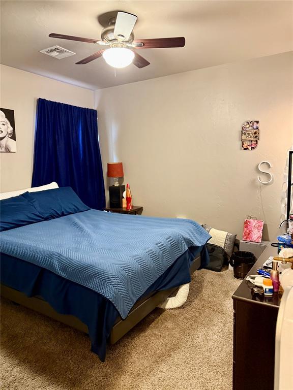 carpeted bedroom with ceiling fan and visible vents