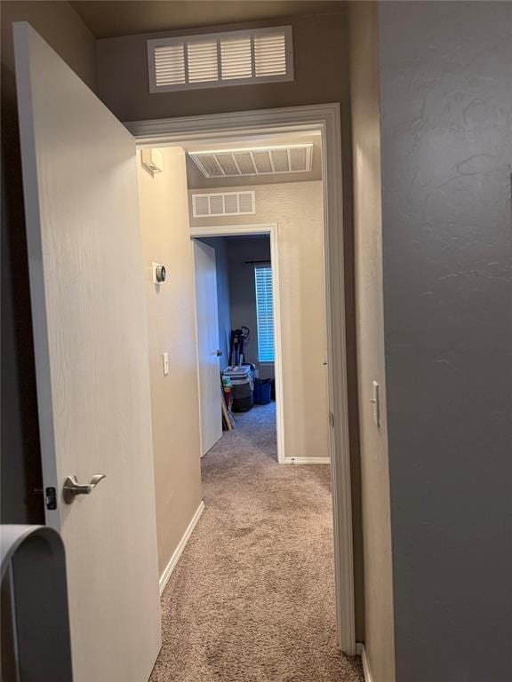 hallway featuring visible vents, baseboards, and carpet floors