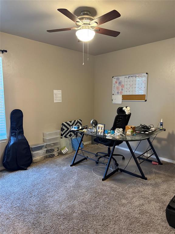 carpeted office space with baseboards and a ceiling fan