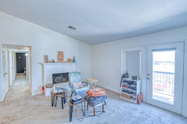 3003 River Oaks Dr Unit 215, Norman, OK 73072 - living area featuring carpet floors, a textured ceiling, a brick fireplace, french doors, and baseboards