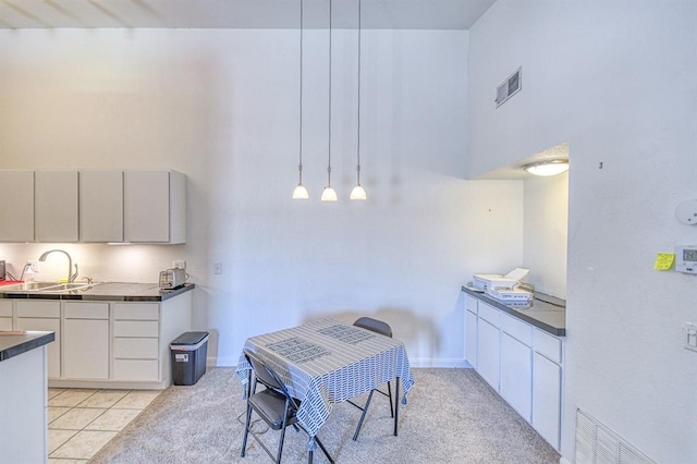 3003 River Oaks Dr Unit 215, Norman, OK 73072 - kitchen with a sink, dark countertops, light tile patterned floors, white cabinets, and hanging light fixtures