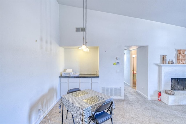3003 River Oaks Dr Unit 215, Norman, OK 73072 - dining area featuring carpet floors, a towering ceiling, a brick fireplace, and baseboards