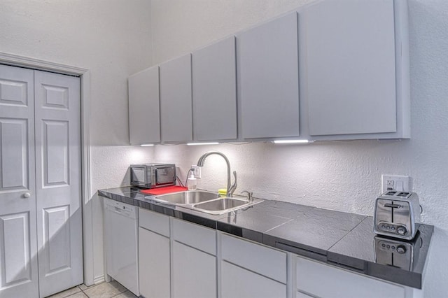 3003 River Oaks Dr Unit 215, Norman, OK 73072 - kitchen with a sink, dishwasher, dark countertops, white cabinetry, and a textured wall