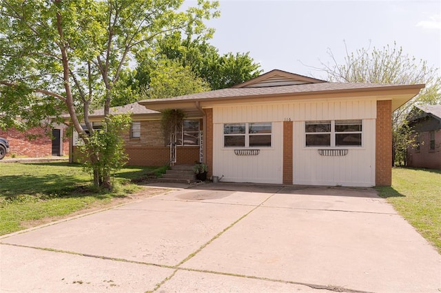 view of front of property featuring concrete driveway, a front yard, and brick siding