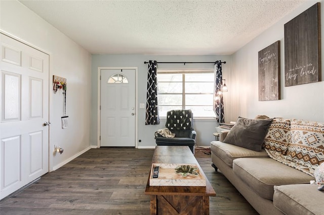 living room with dark wood-type flooring, a textured ceiling, and baseboards