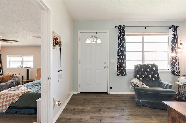 entryway with a textured ceiling, wood finished floors, ceiling fan, and baseboards